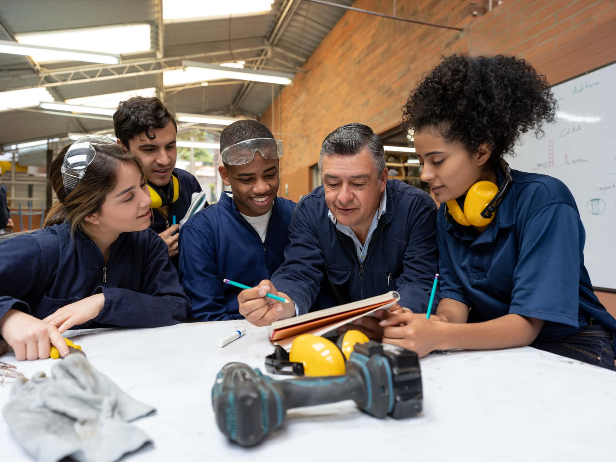 Happy group of Latin American students talking to their teacher in a design class at a workshop https://www.istockphoto.com/photo/group-of-students-talking-to-their-teacher-in-a-design-class-gm1204069341-346314836